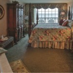 Rehoboth Beach DE Victorian Hotel deluxe room with large bed, wardrobe, tub, and balcony