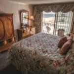 Rehoboth Beach DE Victorian styled hotel king room with large bed, wardrobe, and balcony