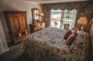 Rehoboth Beach DE Victorian styled hotel king room with large bed, wardrobe, and balcony