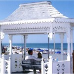 White Gazebo with a swing seating a couple overlooking the ocean
