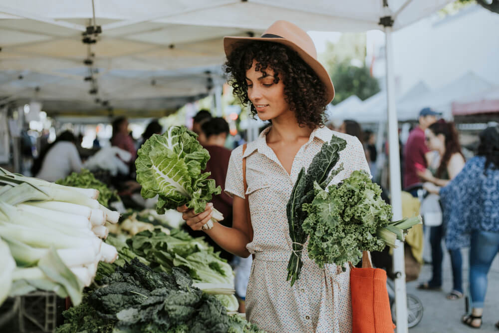 A woman holds up lettuce while shopping at a Rehoboth Beach Farmers Market vendor's booth.