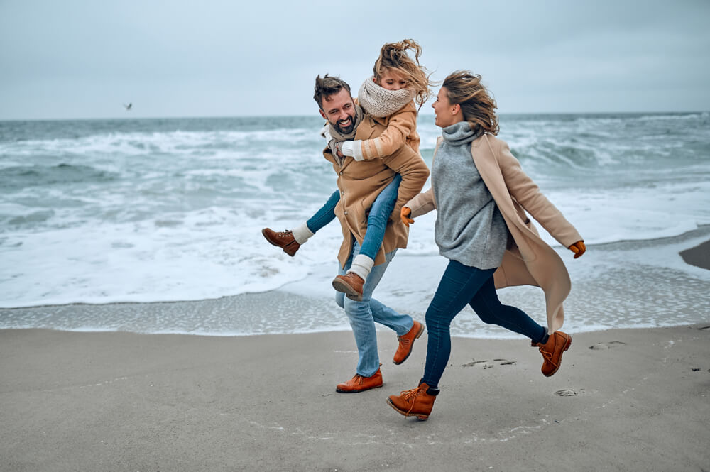 A family of three runs on Rehoboth Beach in the winter.