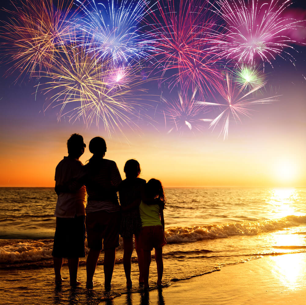 A family stands on Rehoboth Beach, admiring the Fourth of July fireworks show.