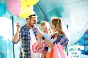 Couple holding toddler daughter with baloons and shopping bags