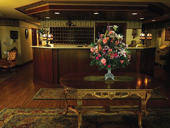 picture of hotel lobby with large flower arrangements on center table and lobby desk behind it