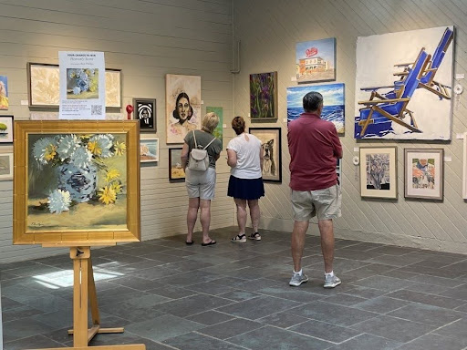 Three people looking at artwork in the Rehoboth Art League campus